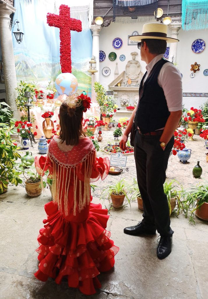 Father and daughter standing in front of a flower cross dressed in traditional attire.